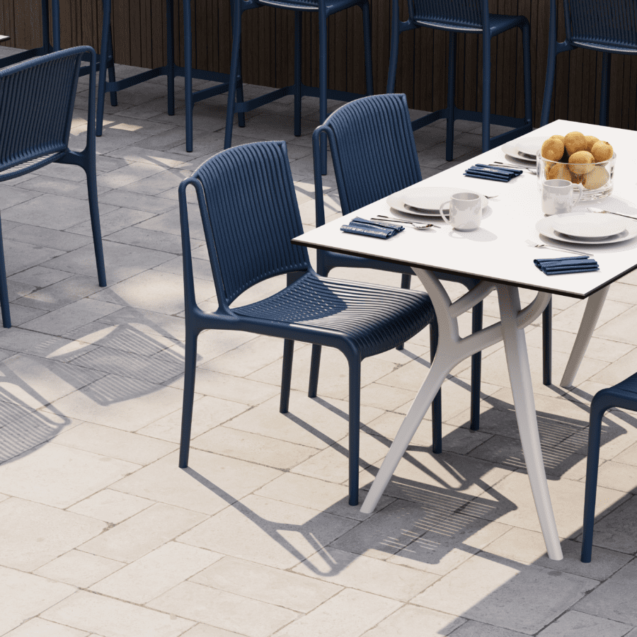 Modern commercial dining space featuring the Ivy table paired with blue hospitality chairs for outdoor restaurant seating.